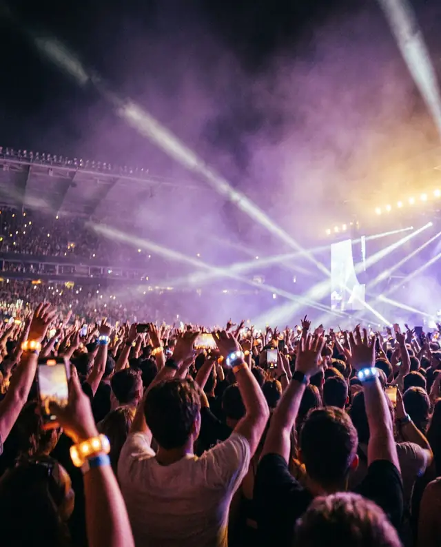 Raised hands and phone lights in a stadium crowd (illustrative image)
